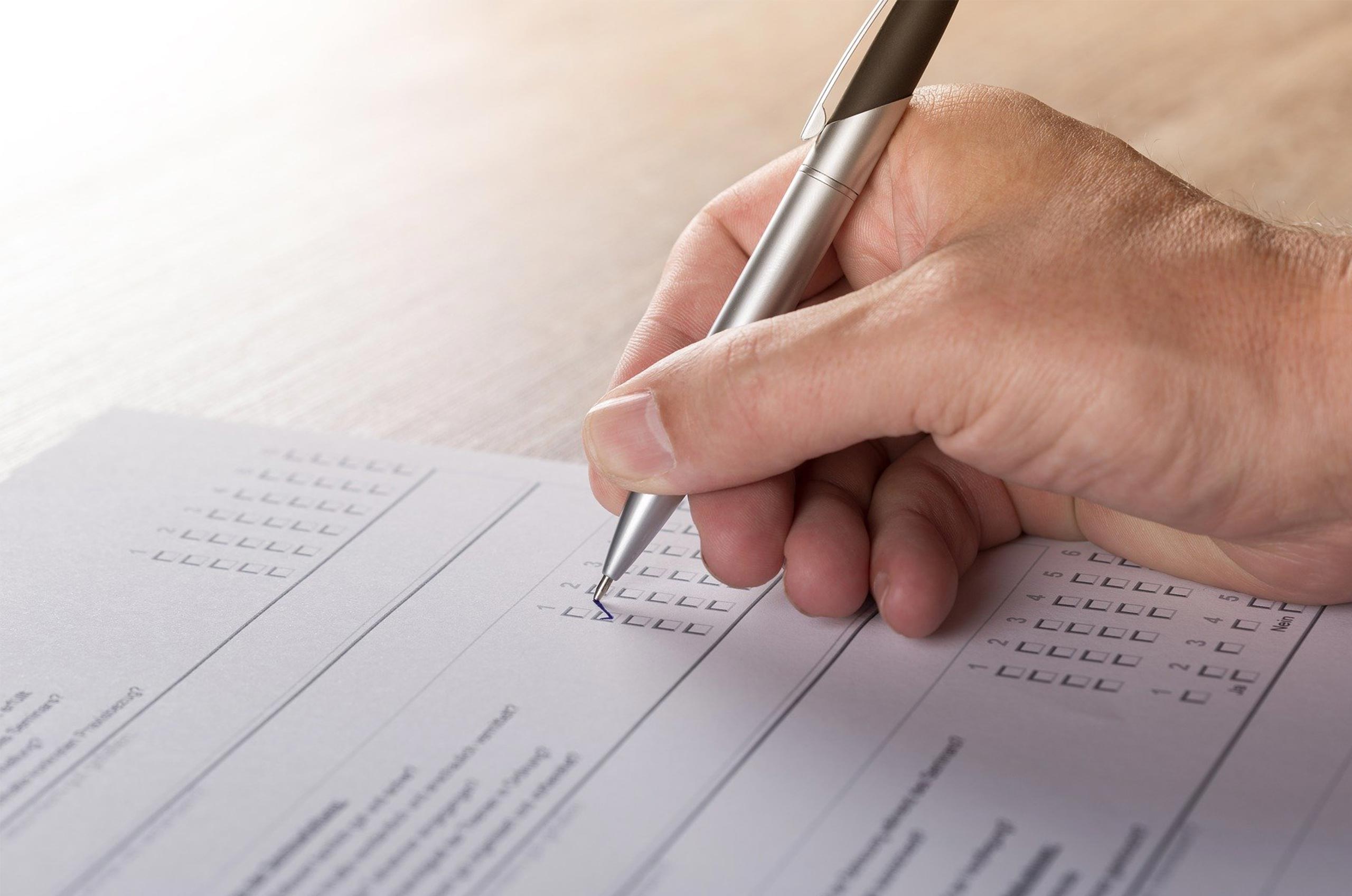 hand writing with a pen onto a survey form